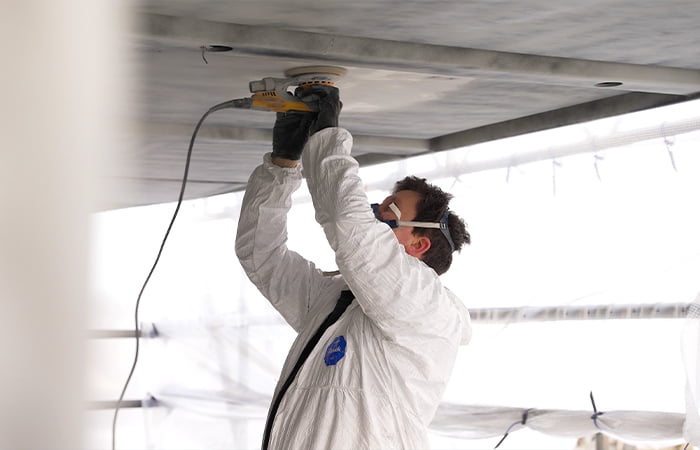 Photo of man sanding yacht in preparation for painting